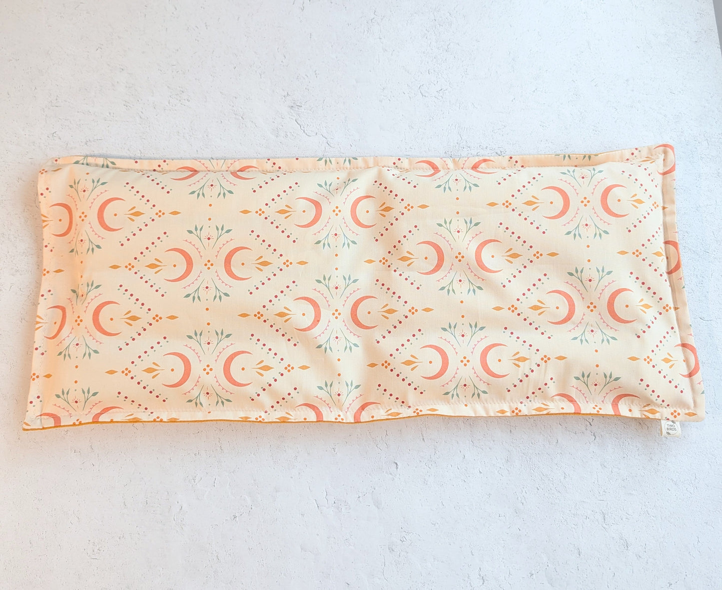 Rectangular weighted heating pad with crescent-floral print and soft mustard underside