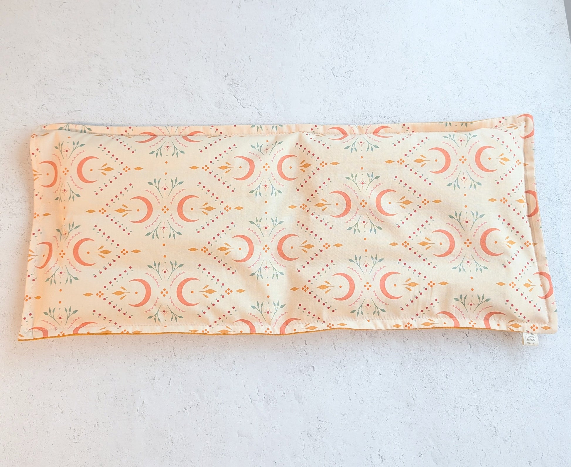 Rectangular weighted heating pad with crescent-floral print and soft mustard underside