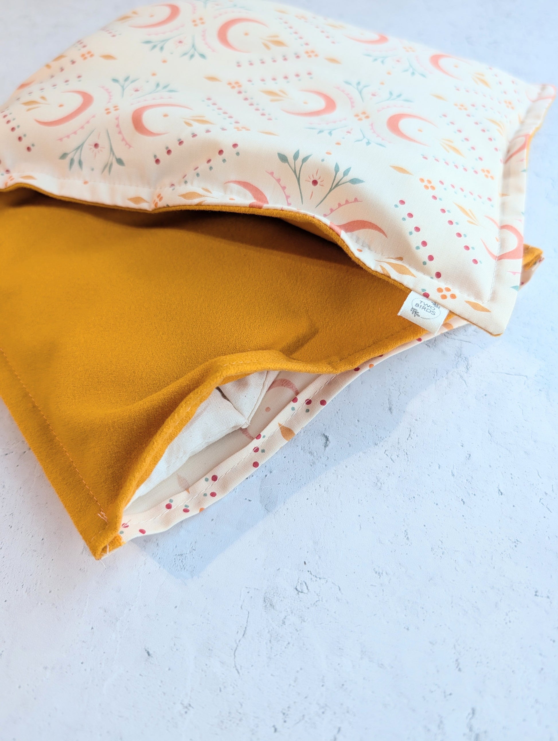 Folded weighted heating pad showing crescent-floral top and mustard flannel layer