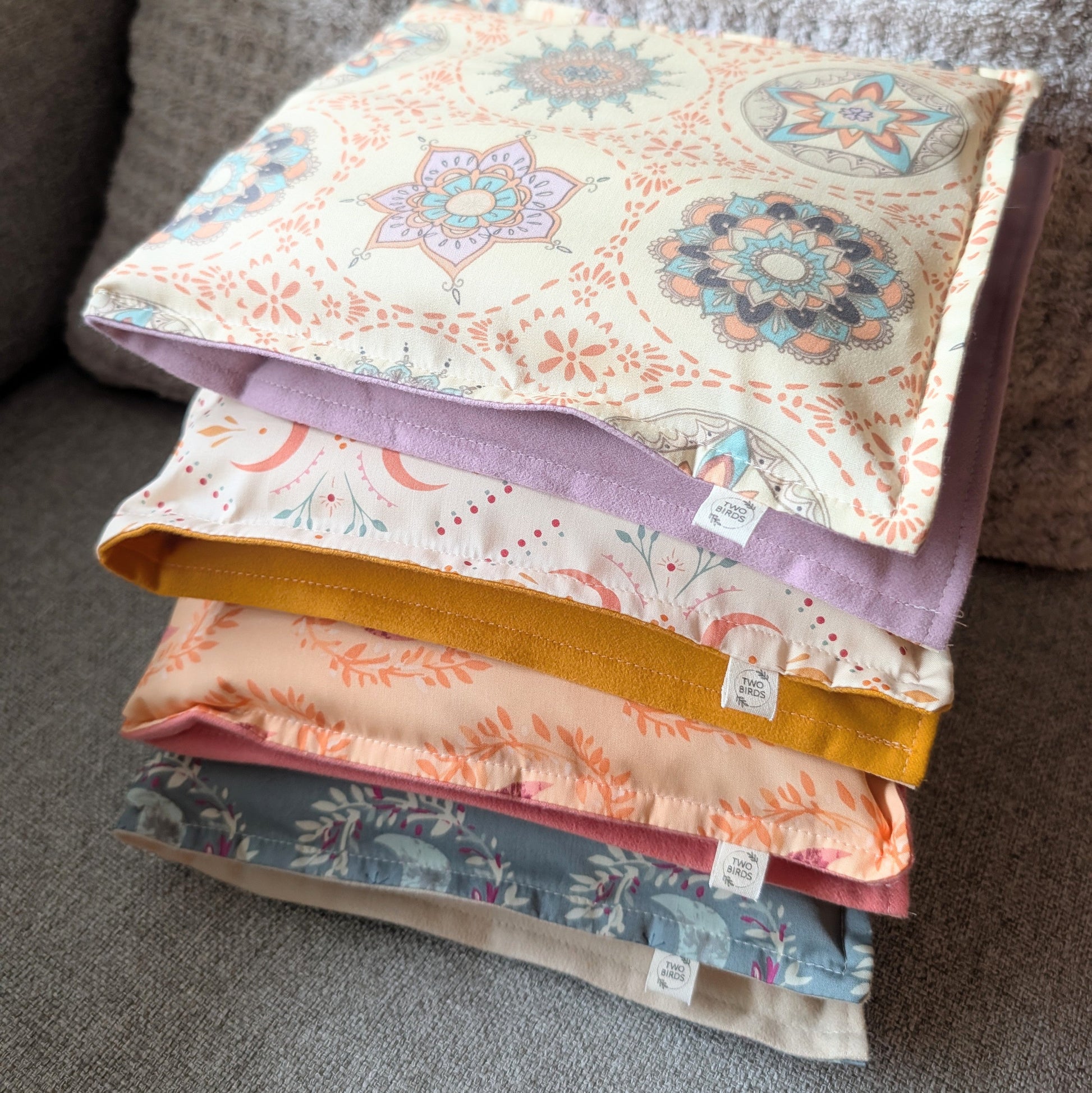 Stacked weighted heating pads with floral cotton flannel covers and colored edges
