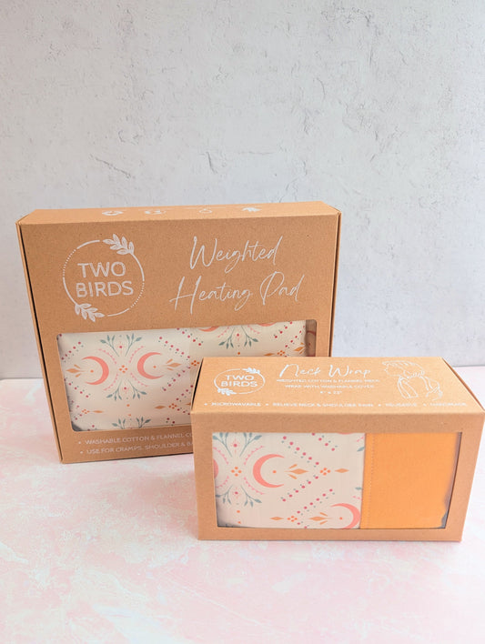 Weighted heating pad in gift boxes; crescent-floral pad with mustard back shown