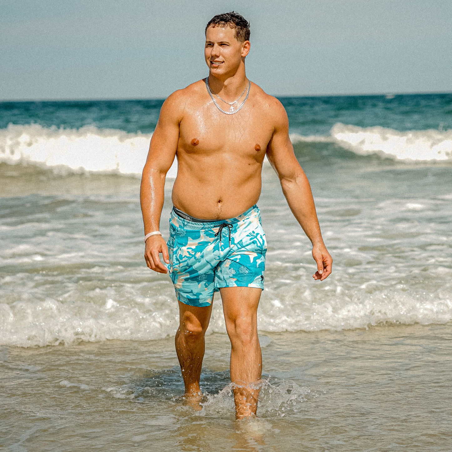 Waterproof swim shorts in turquoise tropical print with elastic waistband and drawstring