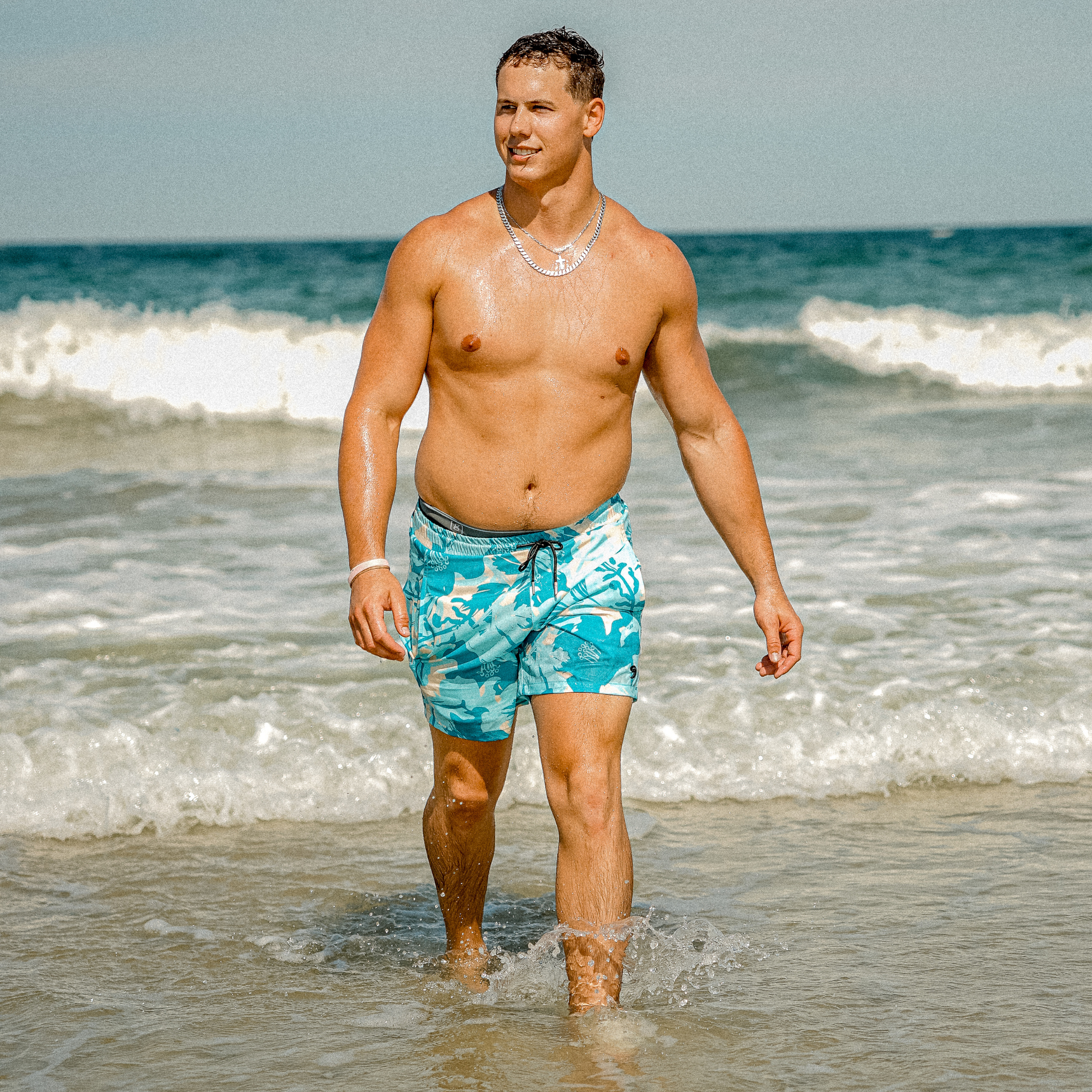 Waterproof swim shorts in turquoise tropical print with elastic waistband and drawstring
