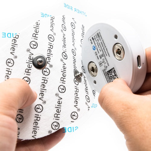 Wireless electrode pod held with fingers, showing CH1 label and contact ports