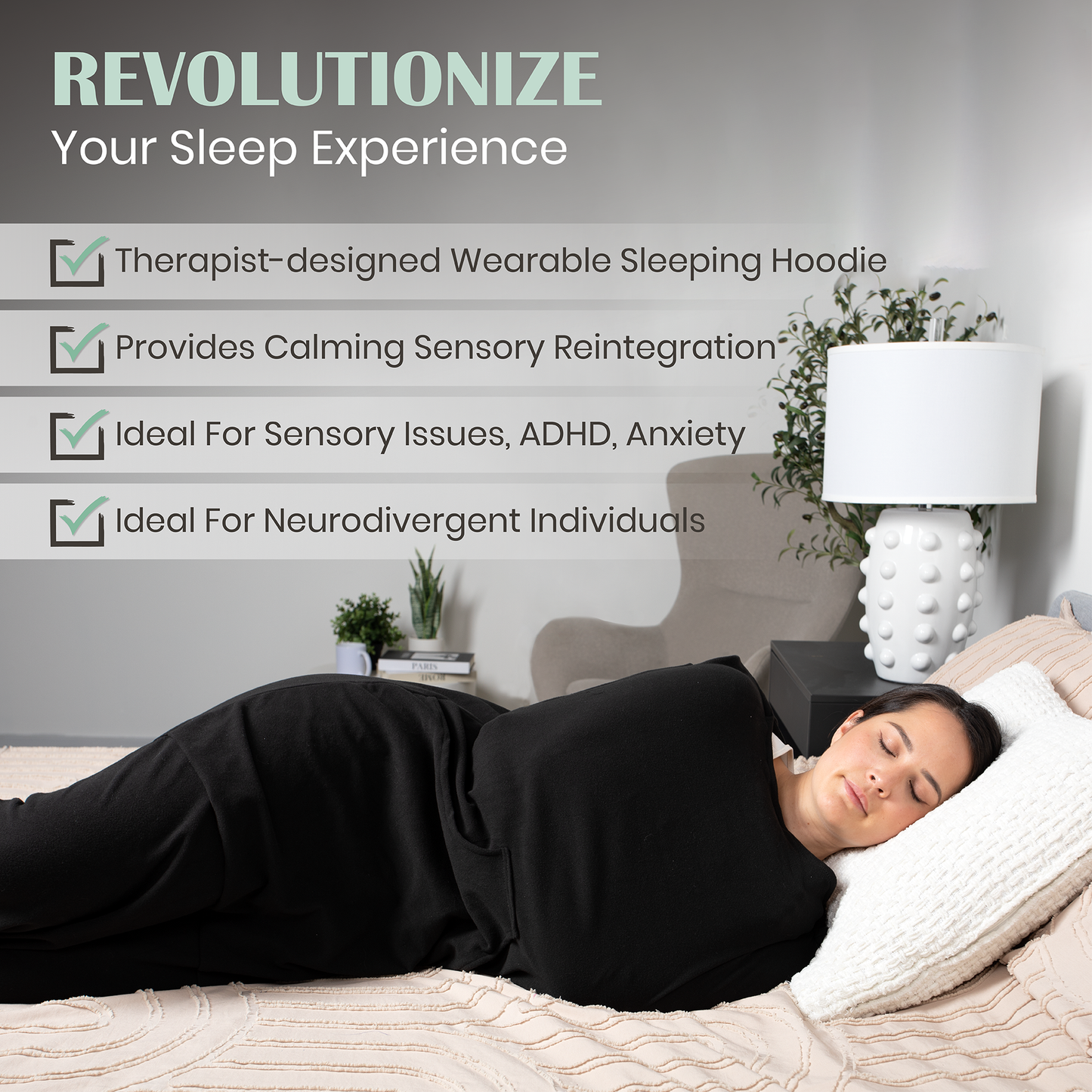 Black wearable compression hoodie-blanket on person lying down, with hood and draped sleeves
