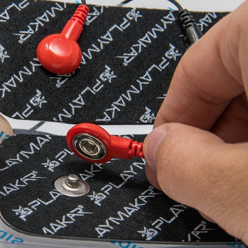 Red electrode snap connector and metal pin on black patterned stimulation pad
