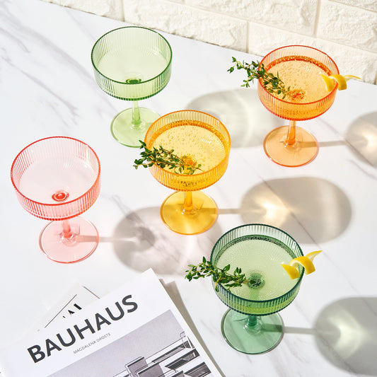 Set of 6 multicolor acrylic coupe cocktail glasses with garnish on table