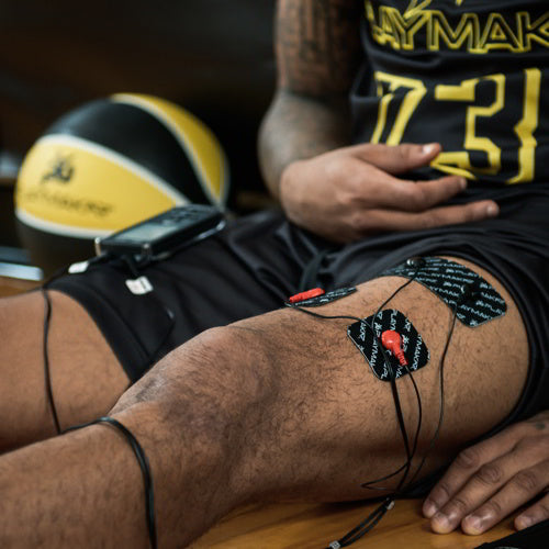 EMS electrode pads attached to thigh with connected wires for stimulation