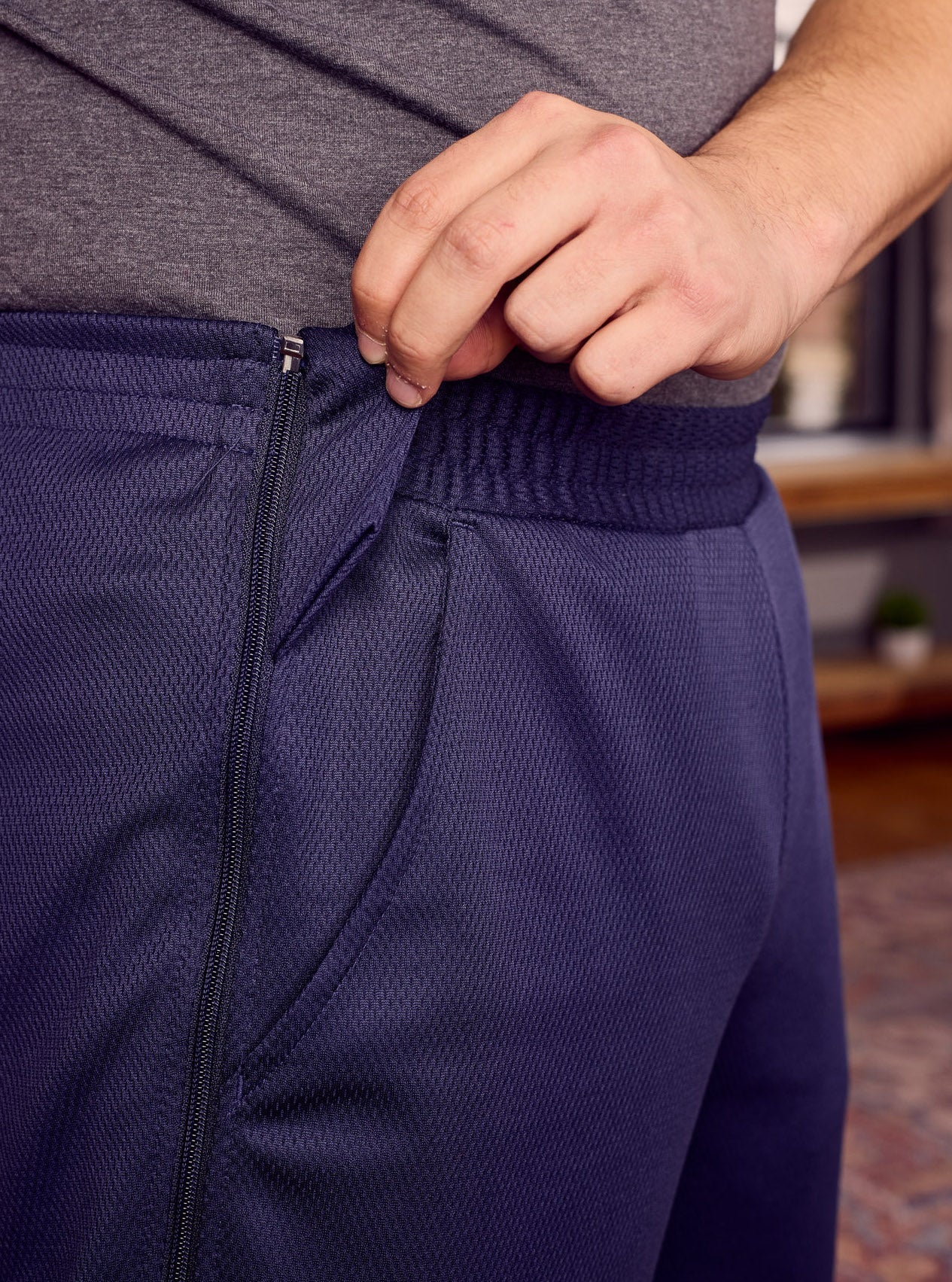 Person wearing navy blue athletic pants with a gray shirt, focusing on the waistband.