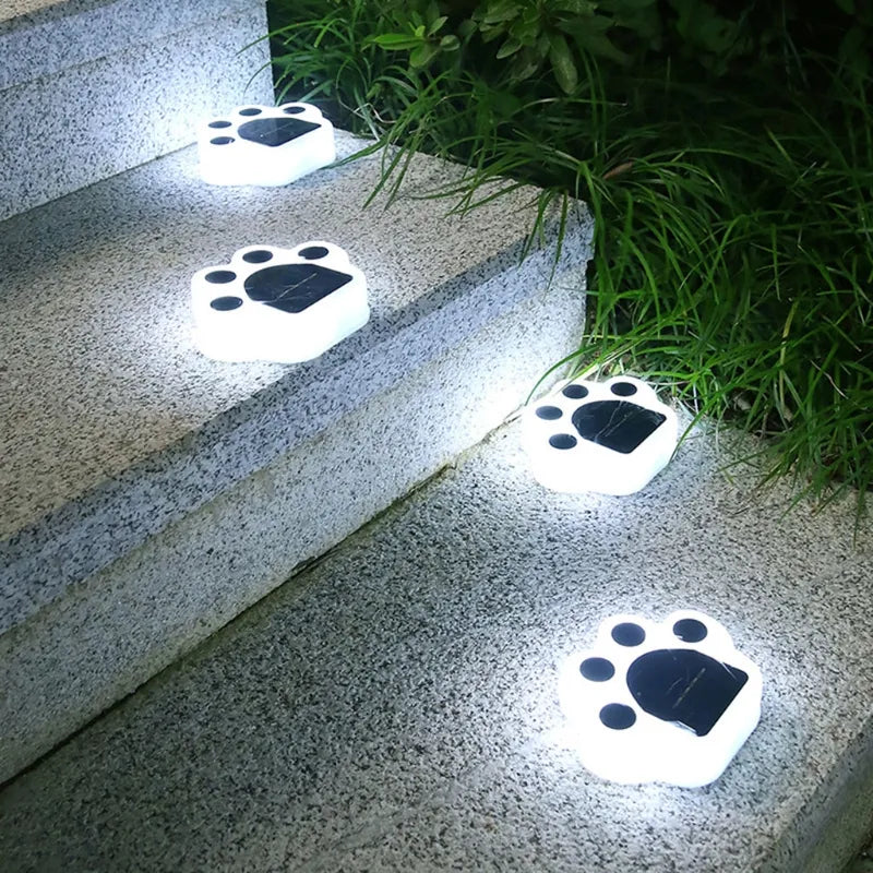White paw-shaped outdoor solar lights with glowing white LED on stone steps