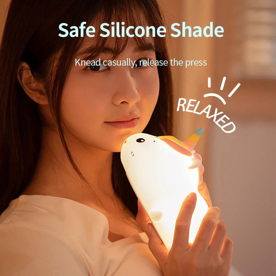Unicorn night light held near a face, glowing warm light with horn.