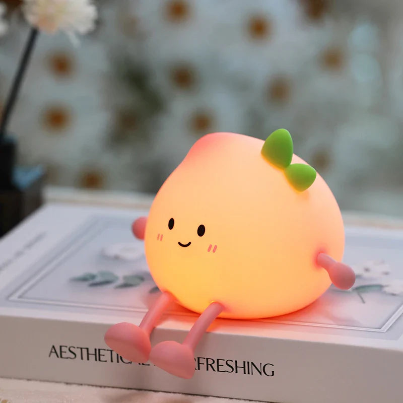 Orange peach-shaped night light with smiling face, green leaf, glowing on display