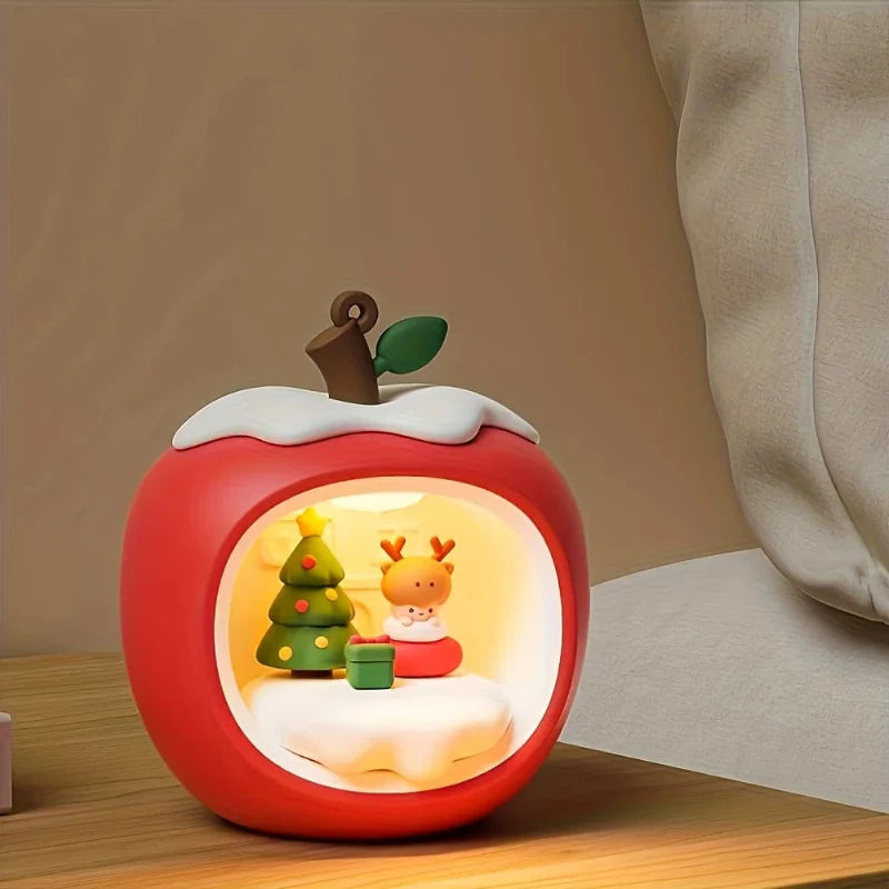 Red apple-shaped night light with decorative holiday figures inside glowing circular window