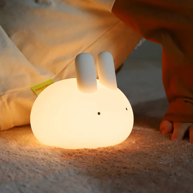 Glowing white bunny night light on a bed