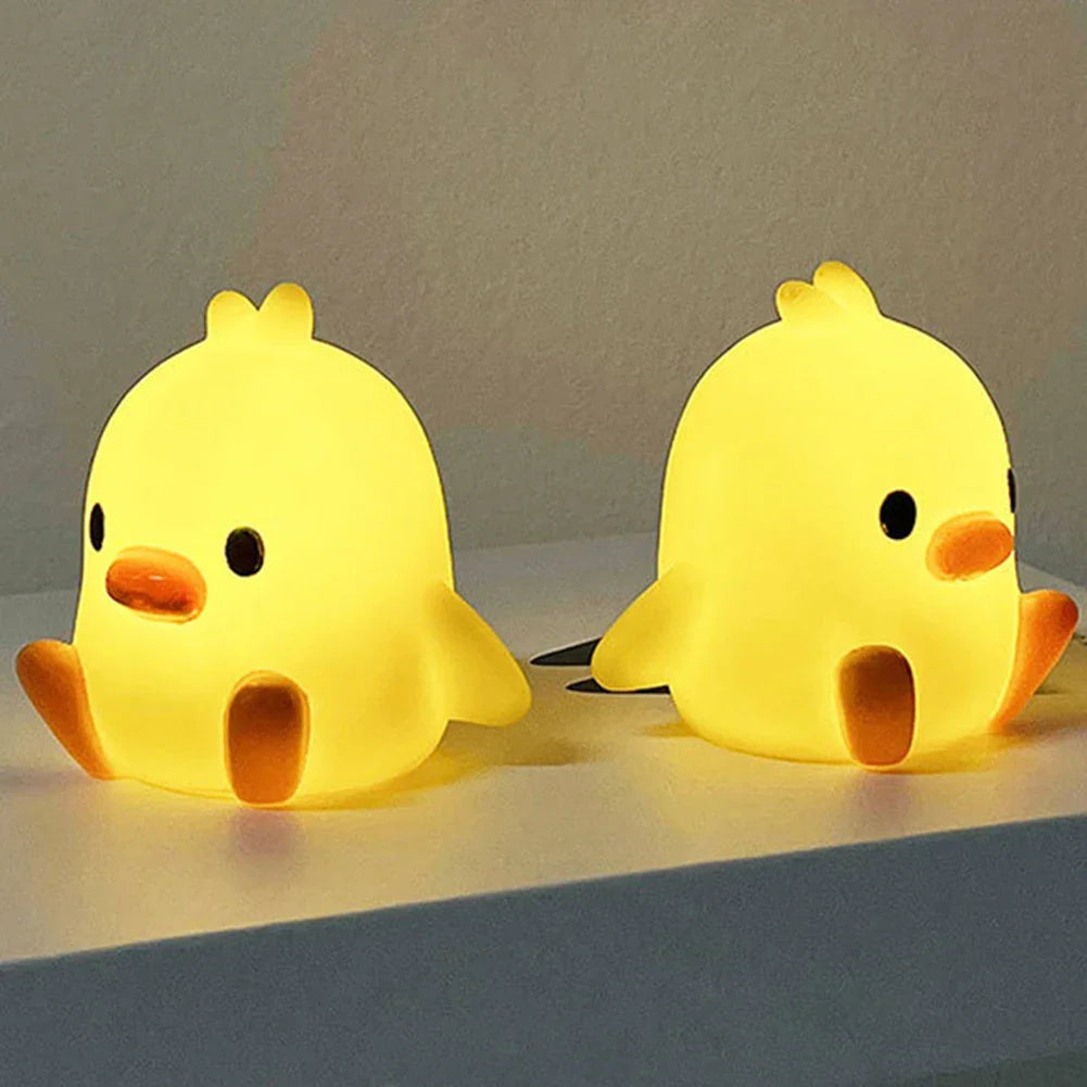 Two duck-shaped night lights, yellow bodies with orange beaks and black eyes
