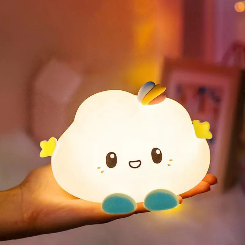 Cloud-shaped LED night light held in hand, glowing white with rainbow wing and face