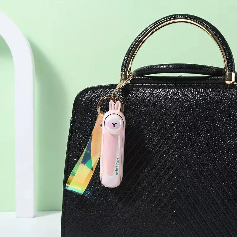 Black animal-shaped handheld fan keychain with pink charm and rainbow strap