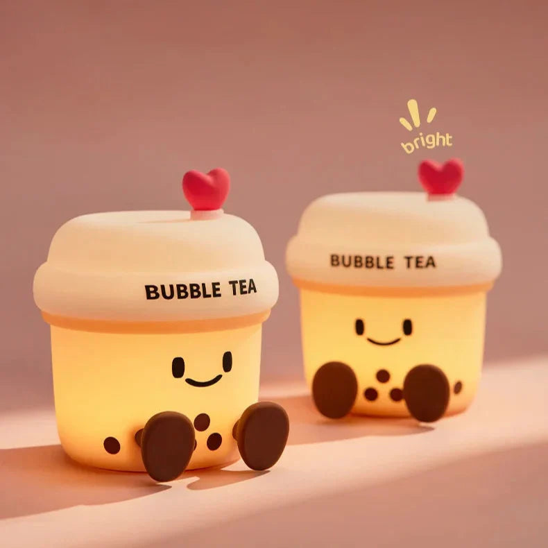 Two kawaii bubble tea cup night lights with glowing faces and heart lids on a tabletop.