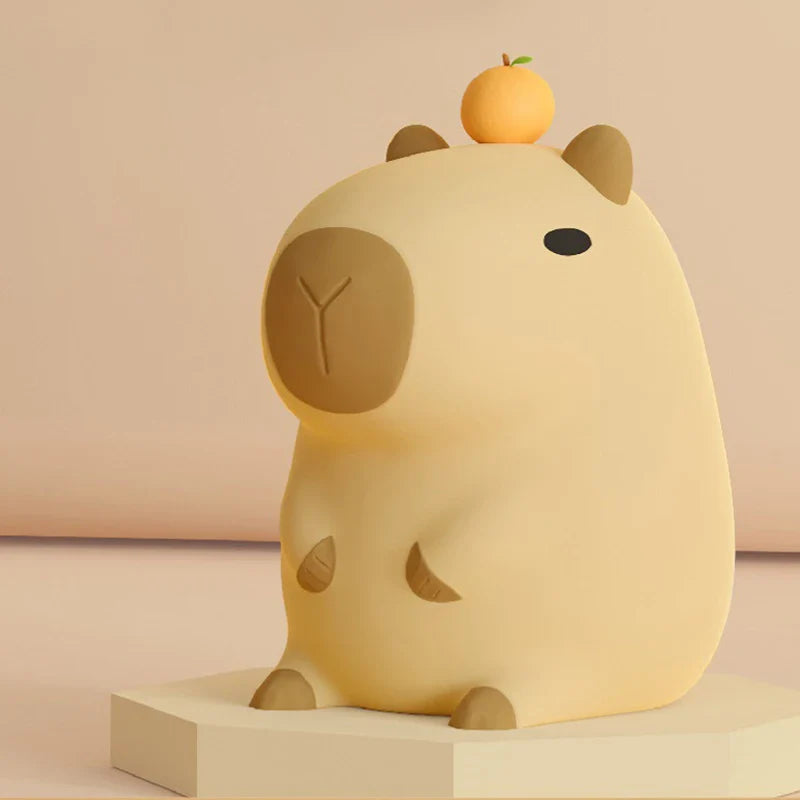 Capybara-shaped night light with soft beige body and small orange knob on top