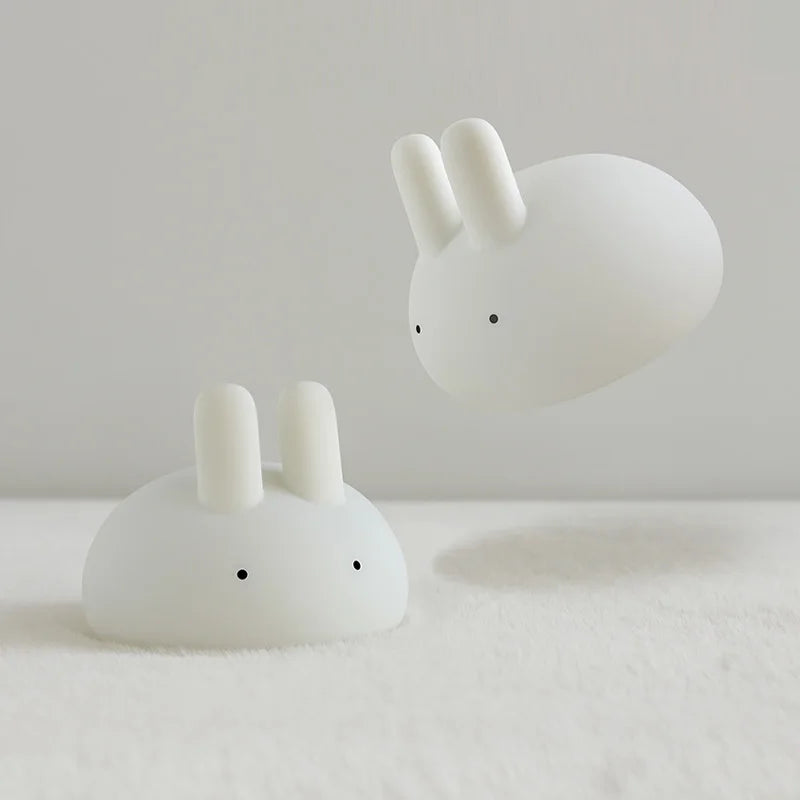 Two white bunny night lights with upright ears on a light surface