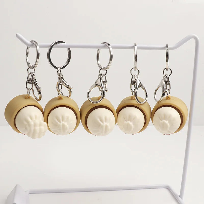Dumpling fidget clicker keychains on display bar, tan containers with faces, metal rings