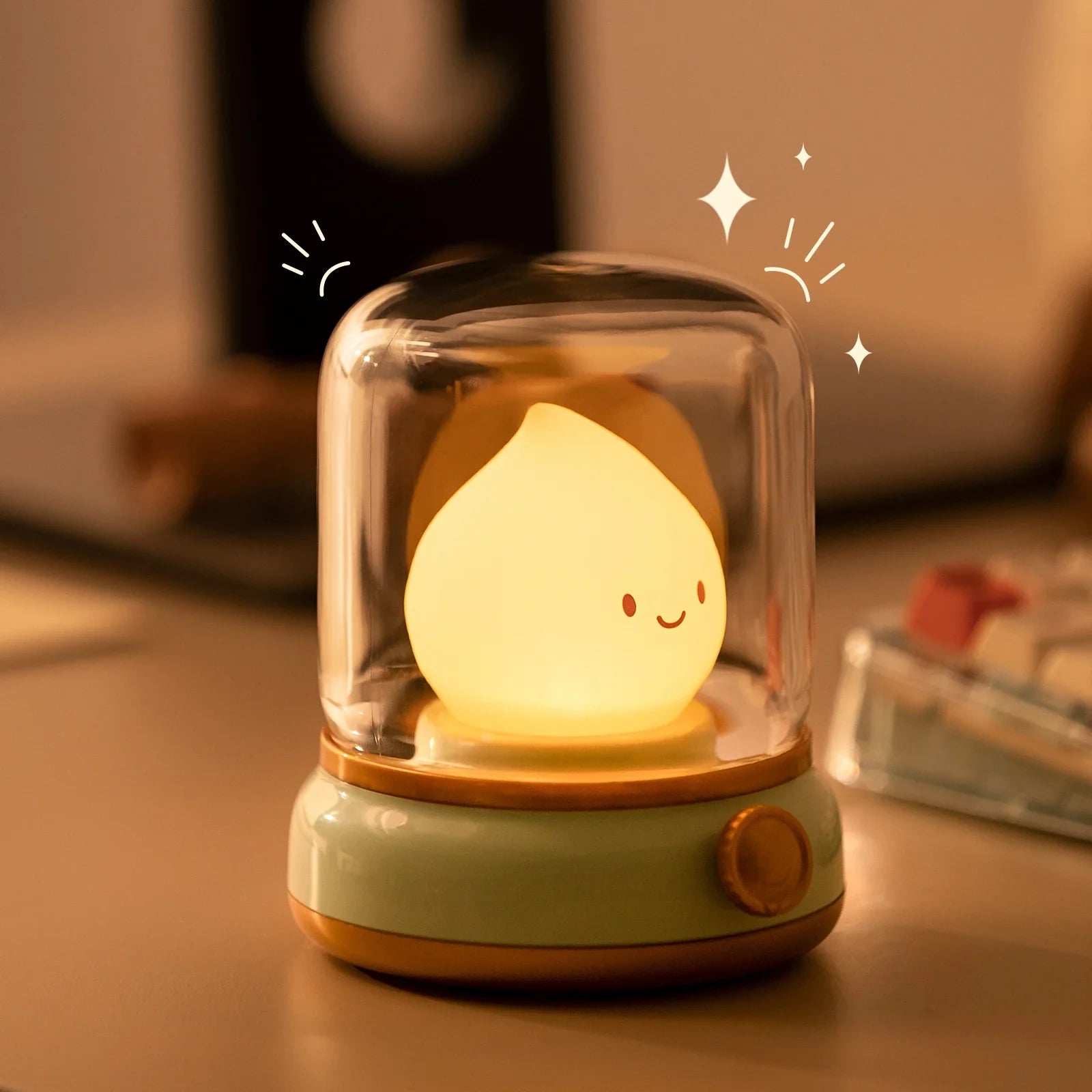 Green flame lantern night light on tabletop with clear dome and glowing smiling flame.