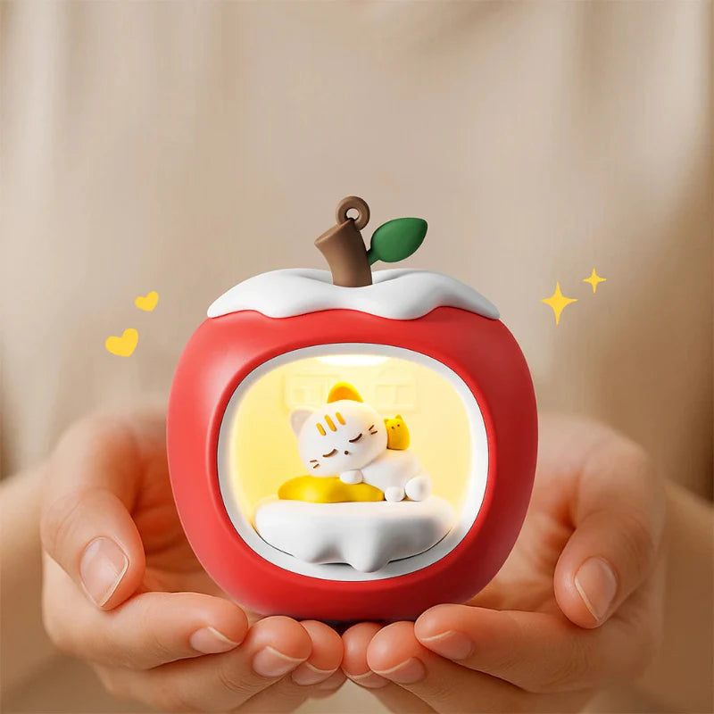Red apple-shaped night light held in hands, glowing circular window with sleeping cat