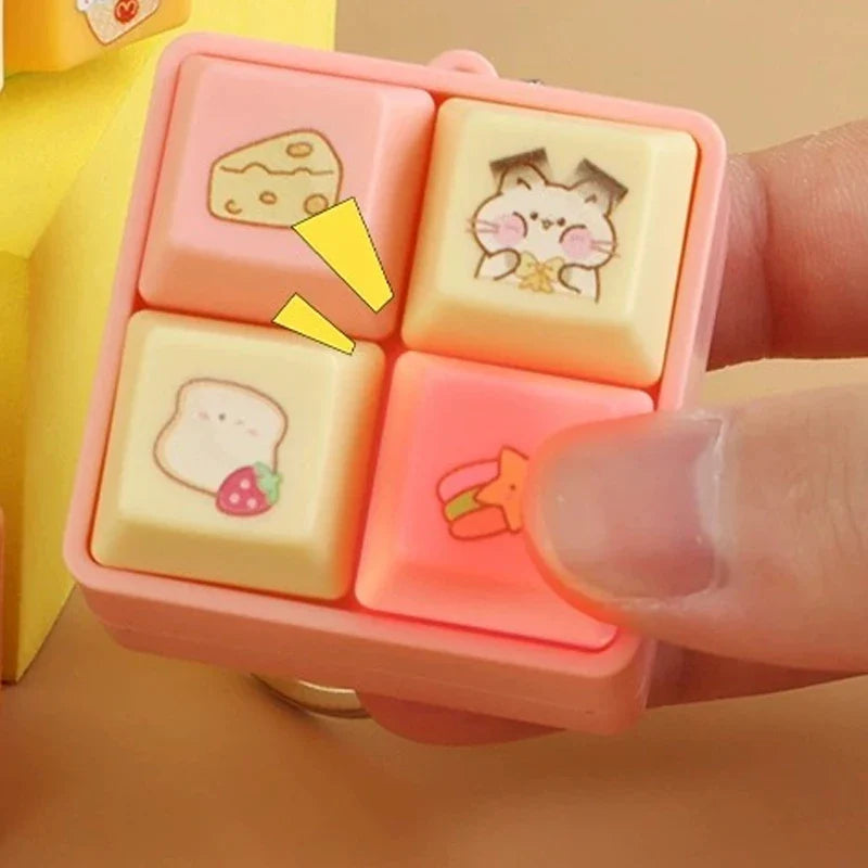 Pink animal fidget clicker keychain cube close-up with cat and mushroom block icons.