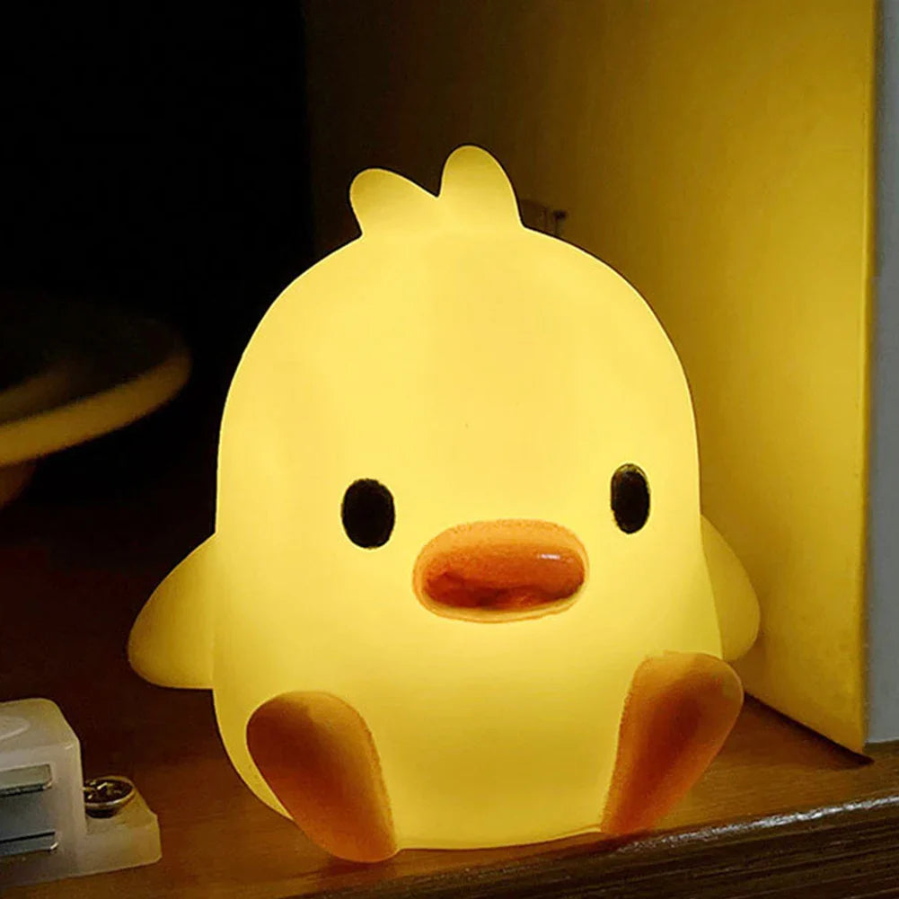 Yellow duck-shaped night light with orange beak, black eyes, and soft glow