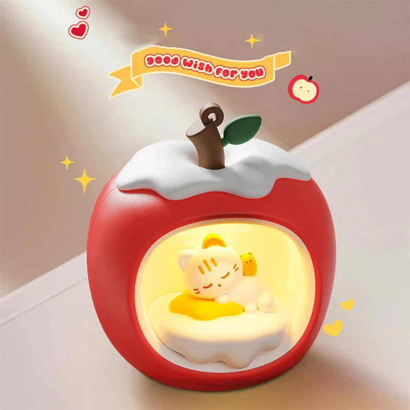 Red apple-shaped night light with sleeping cat scene inside glowing circular panel