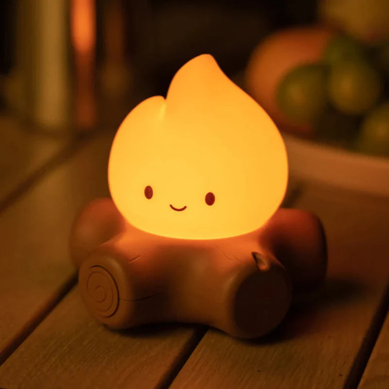 Glowing campfire night light shaped like a smiling flame on a brown log