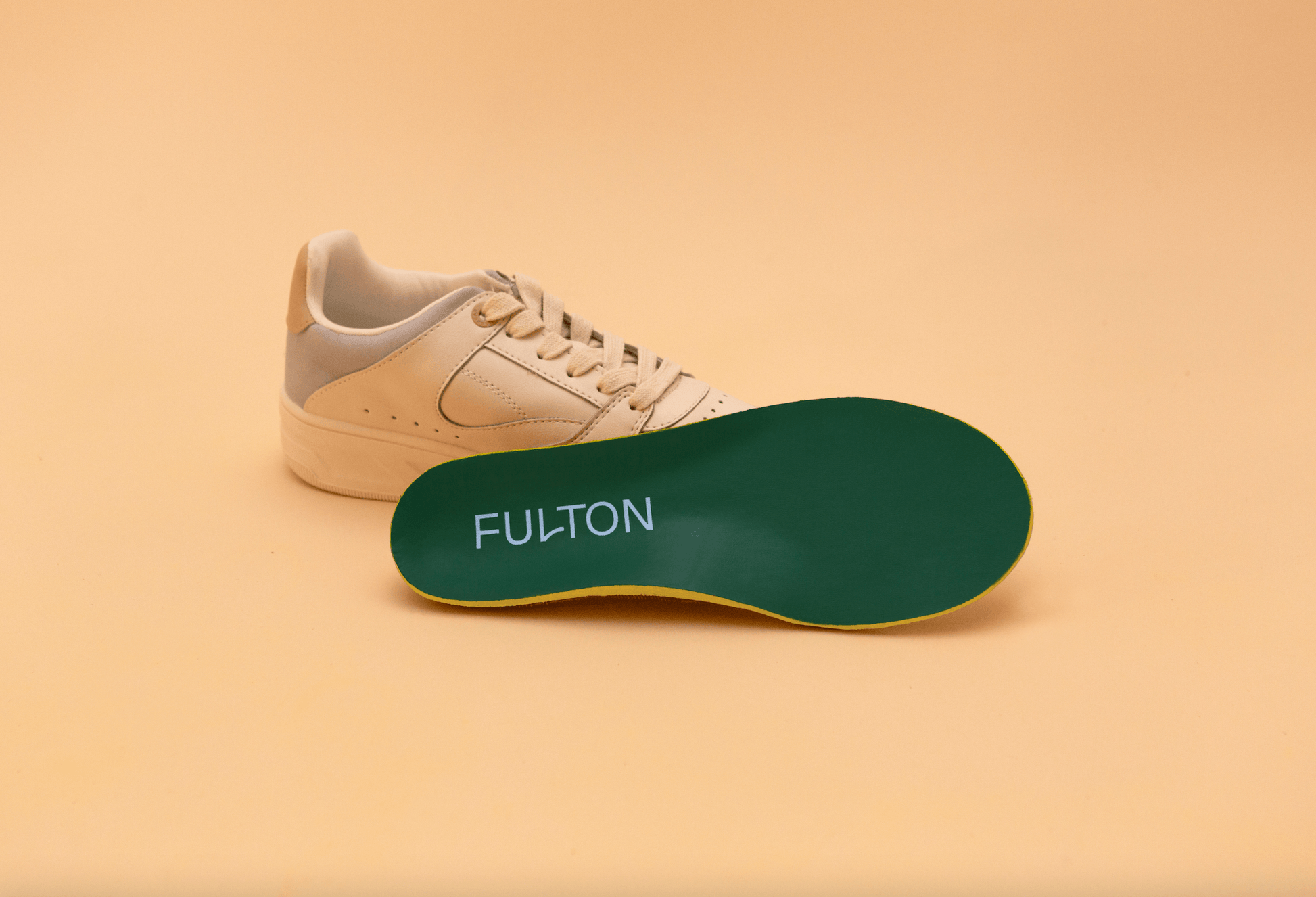 Green FULTON insole placed beside a light-colored sneaker.