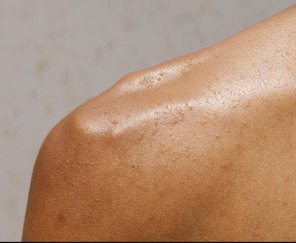 Close-up of a person's shoulder with a neutral background