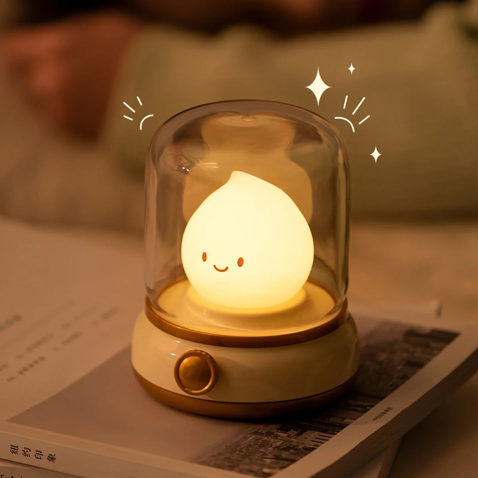 Green flame lantern night light glowing inside clear dome on a book-like surface.