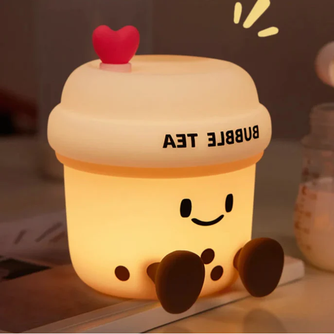 Kawaii bubble tea cup night light glowing with heart lid and dark topping circles at base.