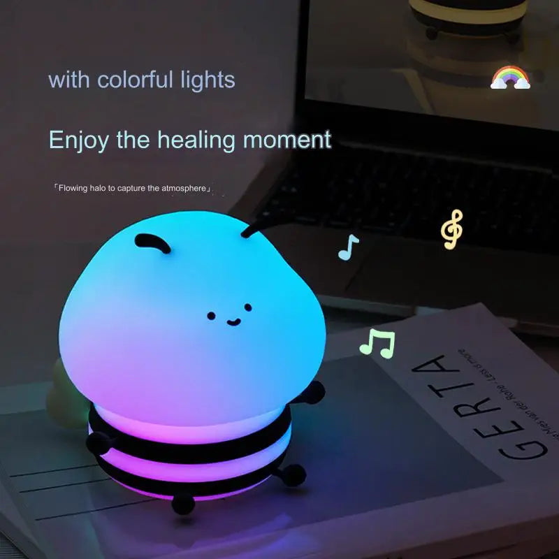 Bee-shaped night light on a desk with blue-to-purple glow and music-note themed icons