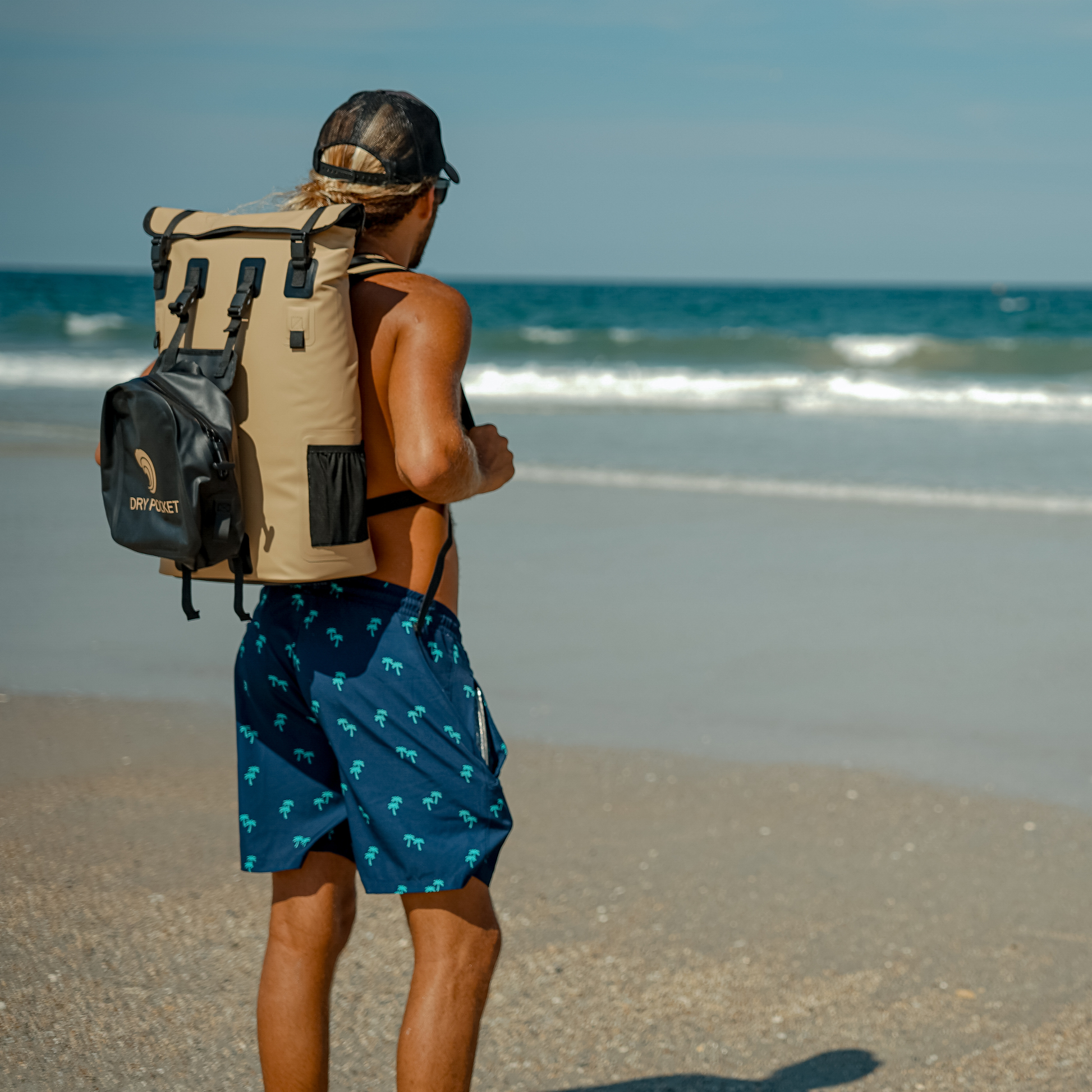 Waterproof floating backpack cooler worn outdoors, beige with black straps and DRY POCKET pouch