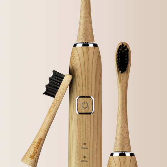 Bamboo electric toothbrush with black bristles and power button on wooden handle