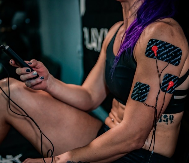 EMS muscle stimulator electrode pads on forearm and leg with connected wires