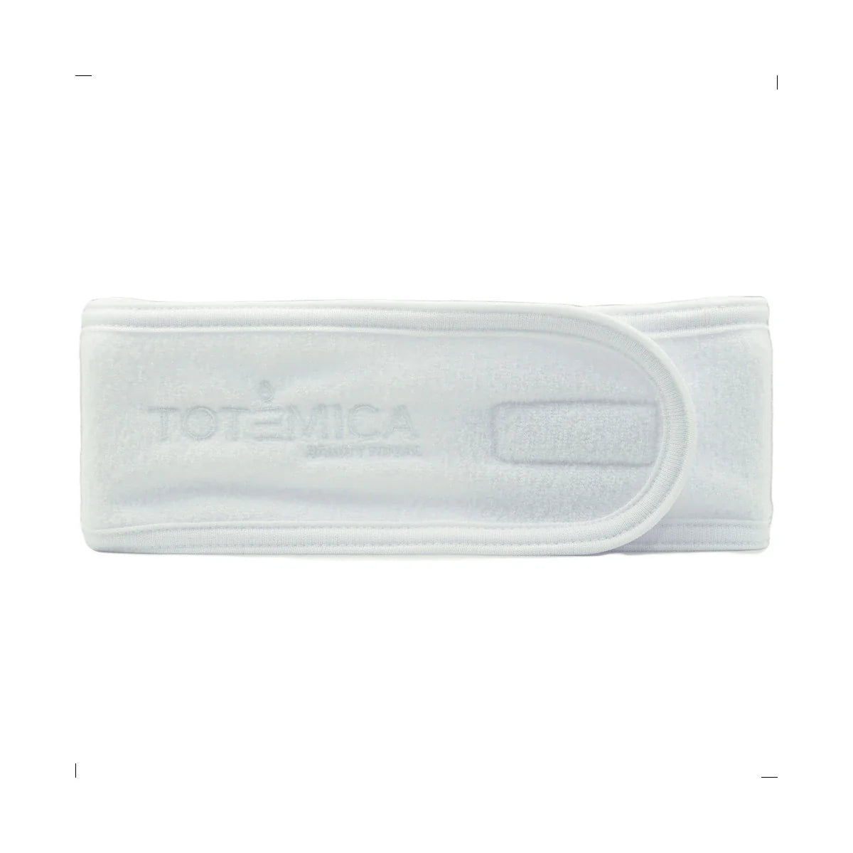 Adjustable spa headband in white terry fabric, centered clasp and subtle logo