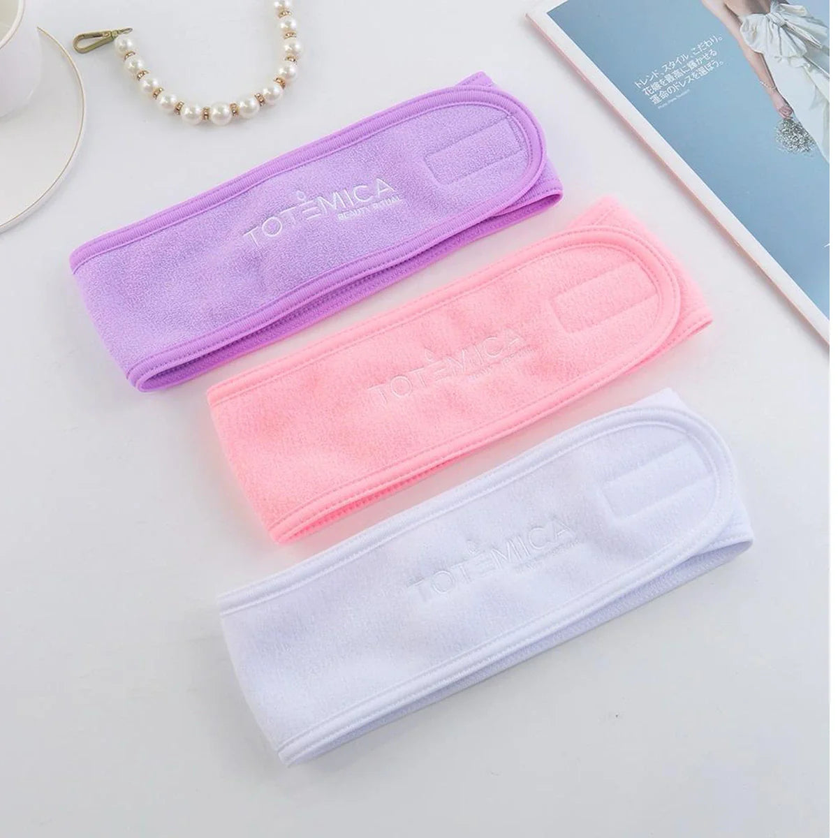Set of three spa headbands: lavender, pink, and white, each with Totemica logo