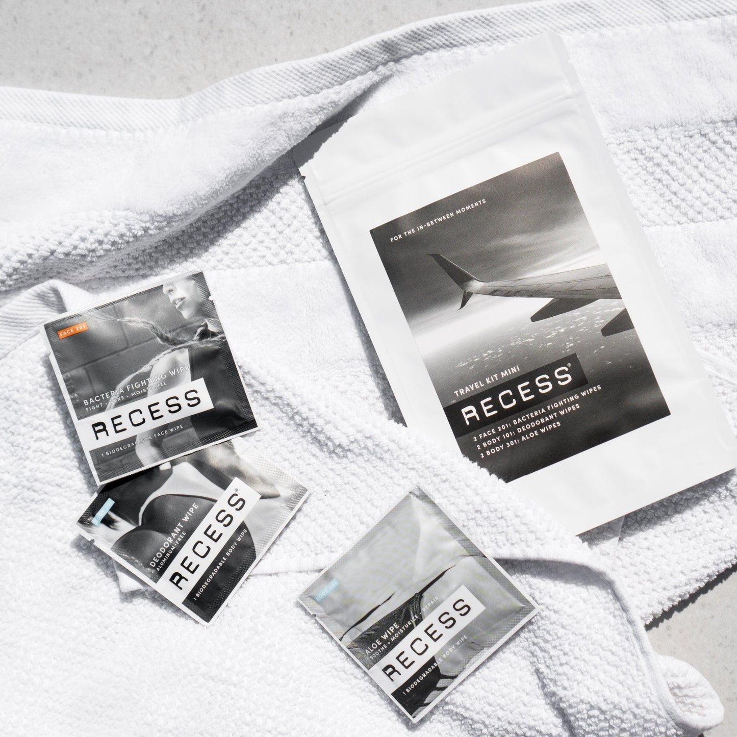 Travel kit mini wipes packets laid on a textured towel.