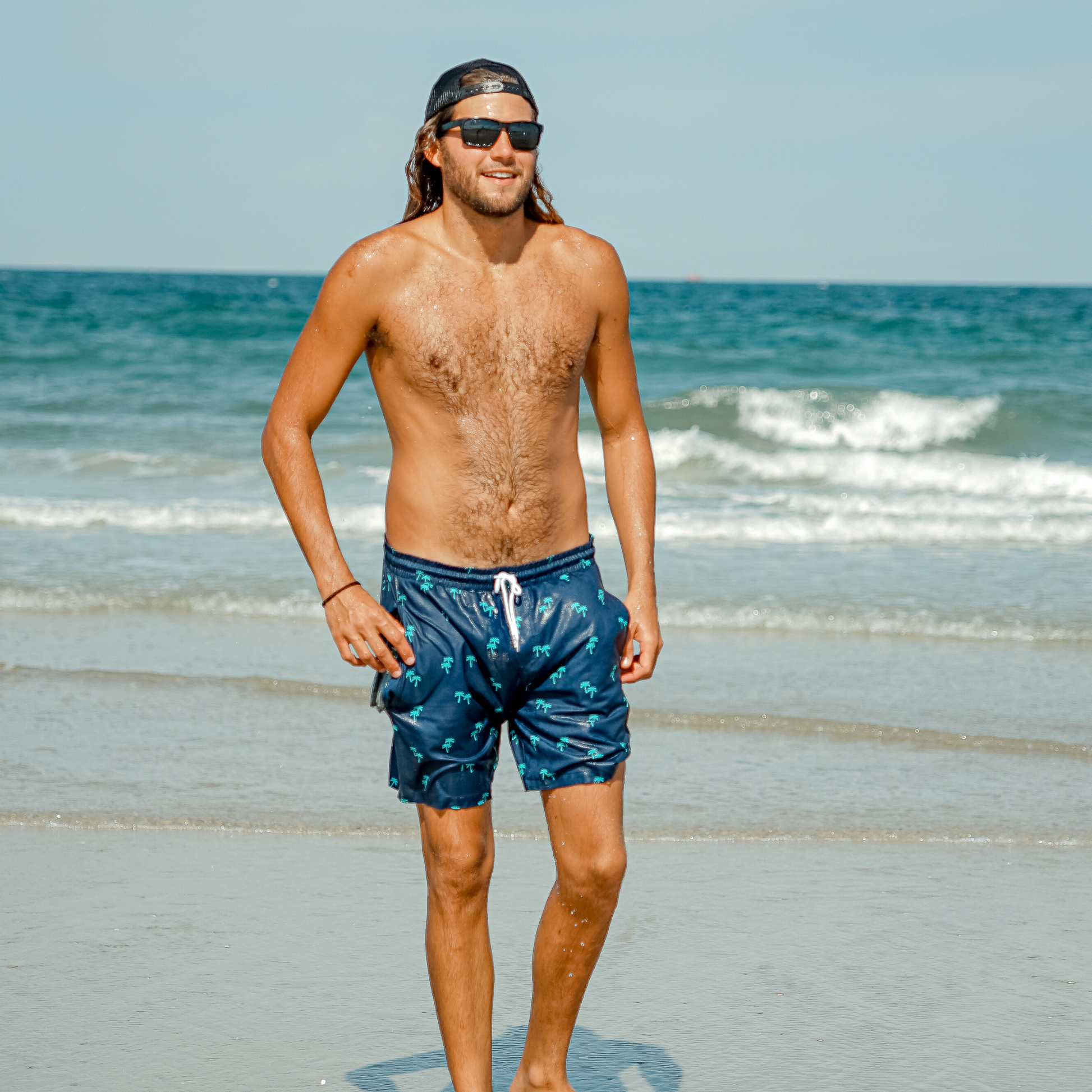 Men's teal swim shorts with dark palm tree print and drawstring waist
