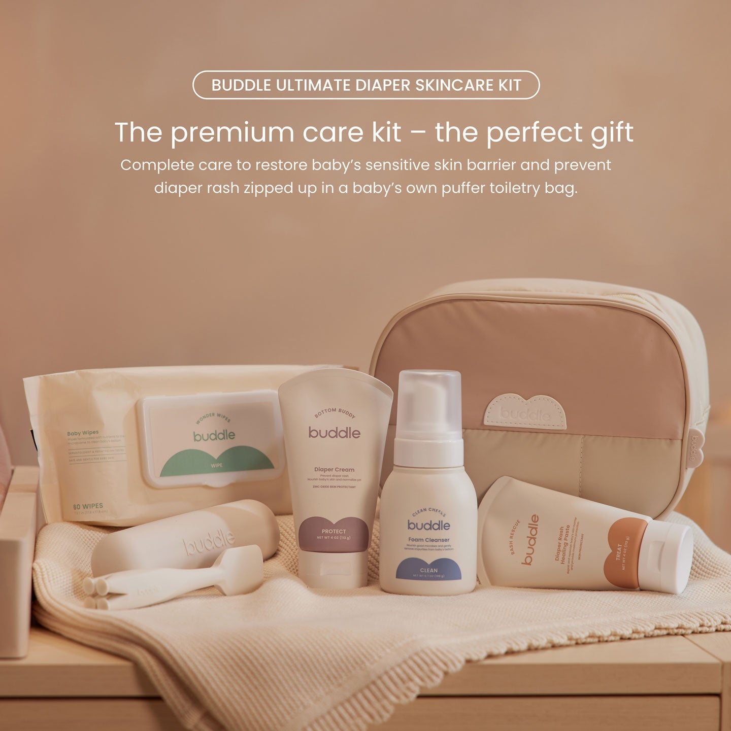 Diaper skincare kit on blanket with zip toiletry bag, wipes, and skincare bottles