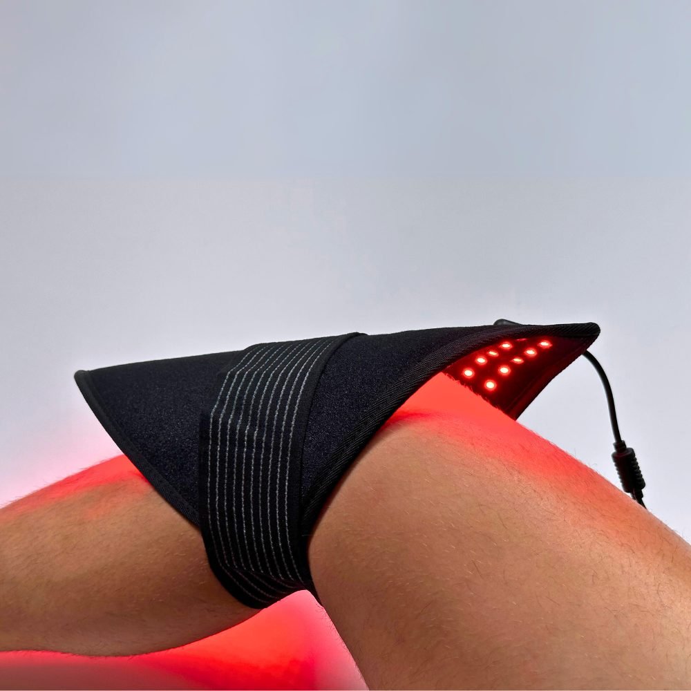 Black LED therapy pad strapped on leg with red glowing dot array