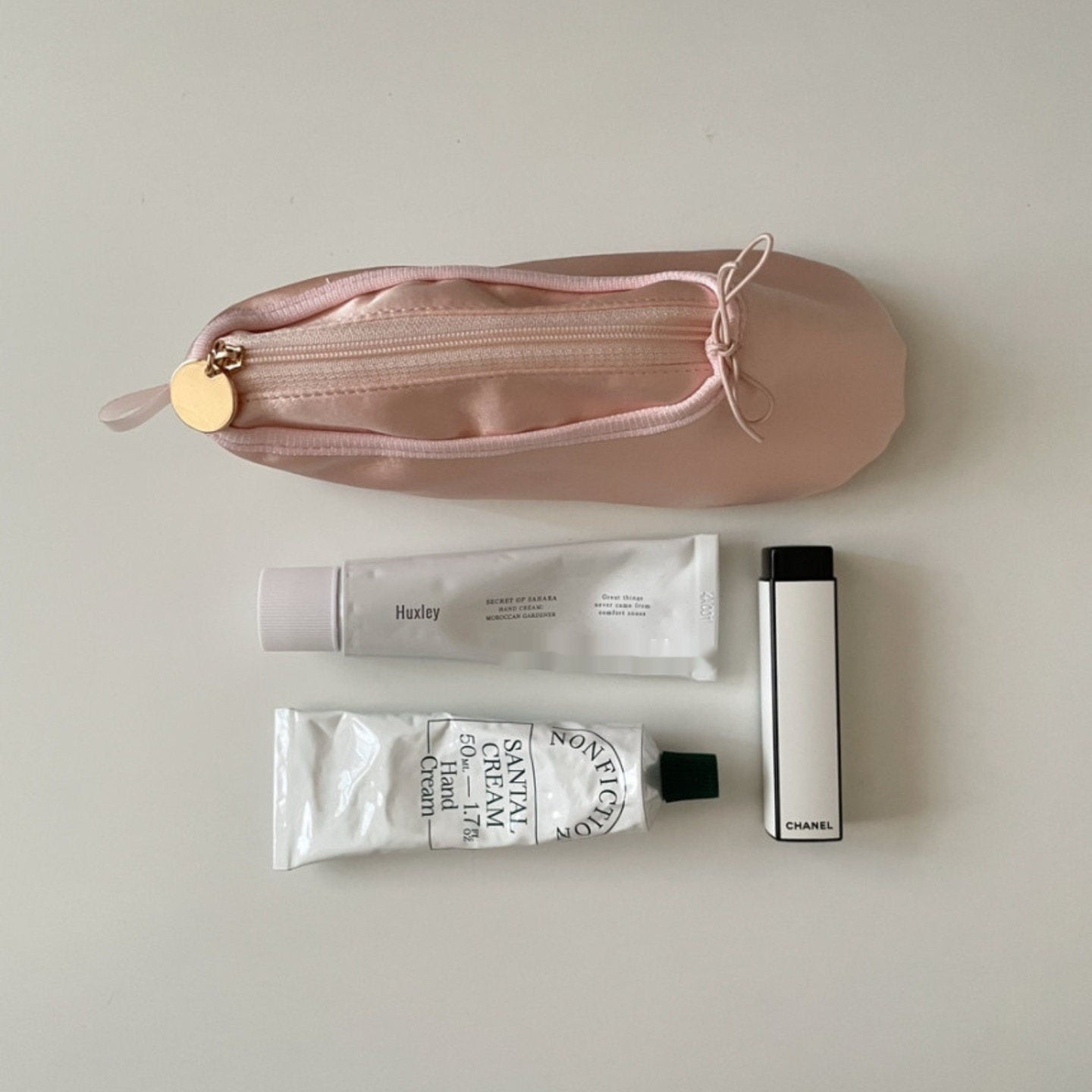 Pink ballet shoe pouch with gold zipper pull and ribbon bow top