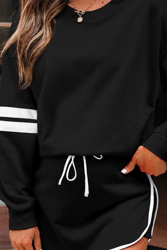 Black pullover with varsity white sleeve stripes, drawstring mini skirt, and round neckline.