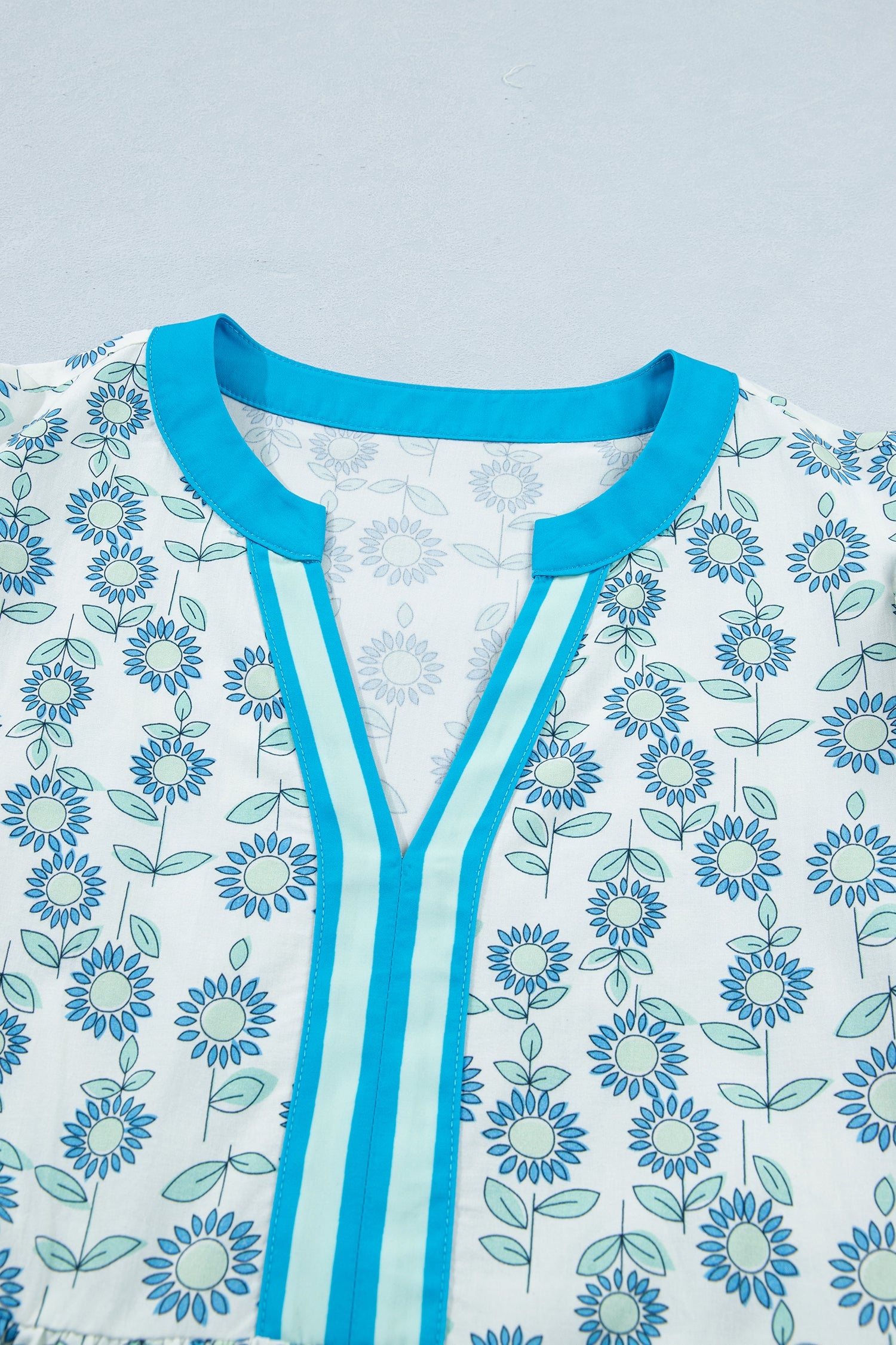 Neckline of sky blue floral mini dress with blue-trim V placket and crew neck