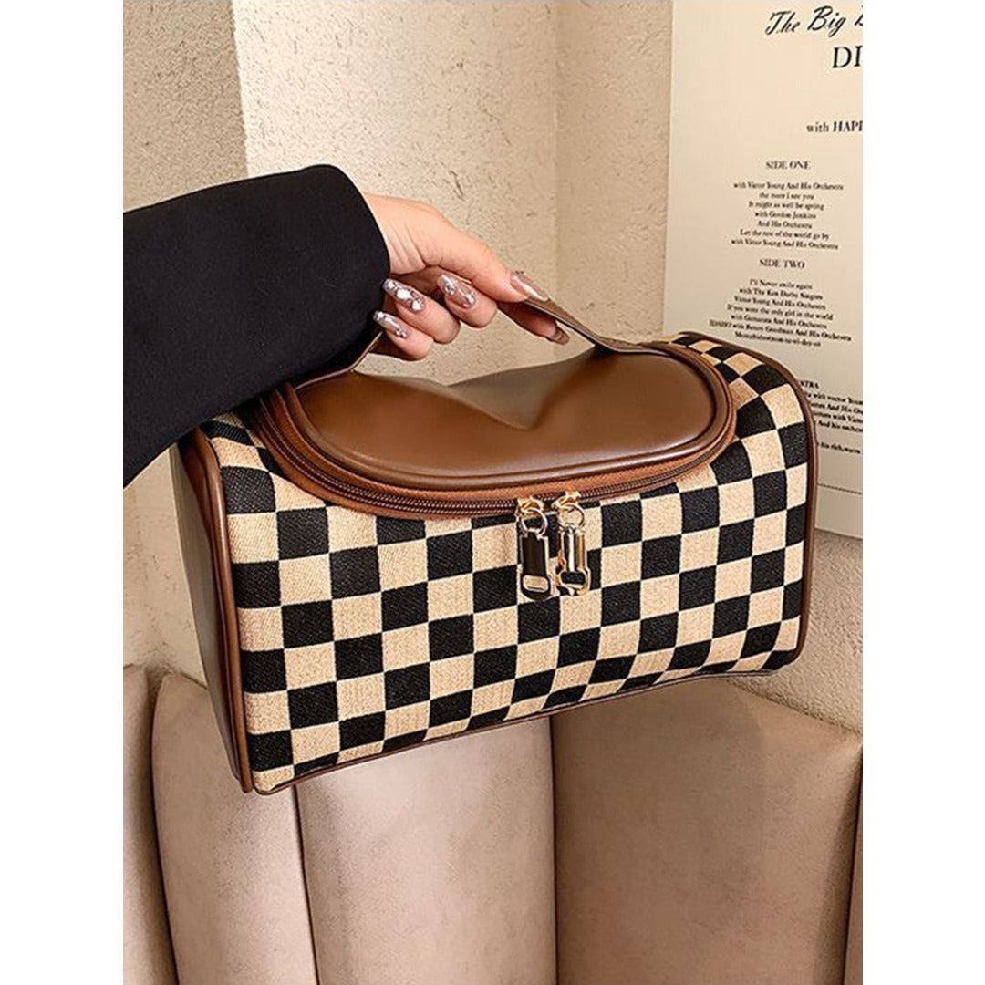 Plaid cosmetic bag with brown top flap and zipper, held open on a seat