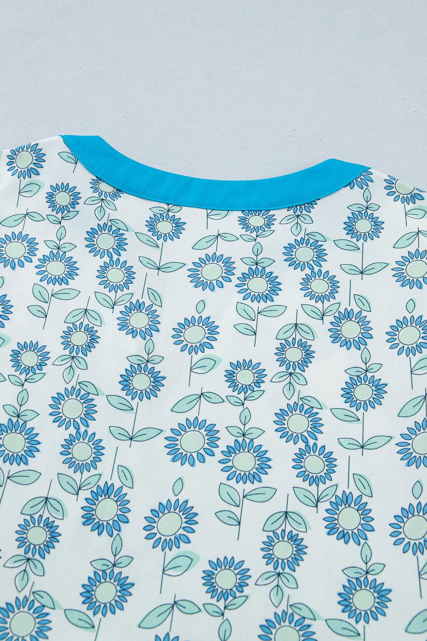 Shoulder and yoke of sky blue floral mini dress with blue crew neckline trim